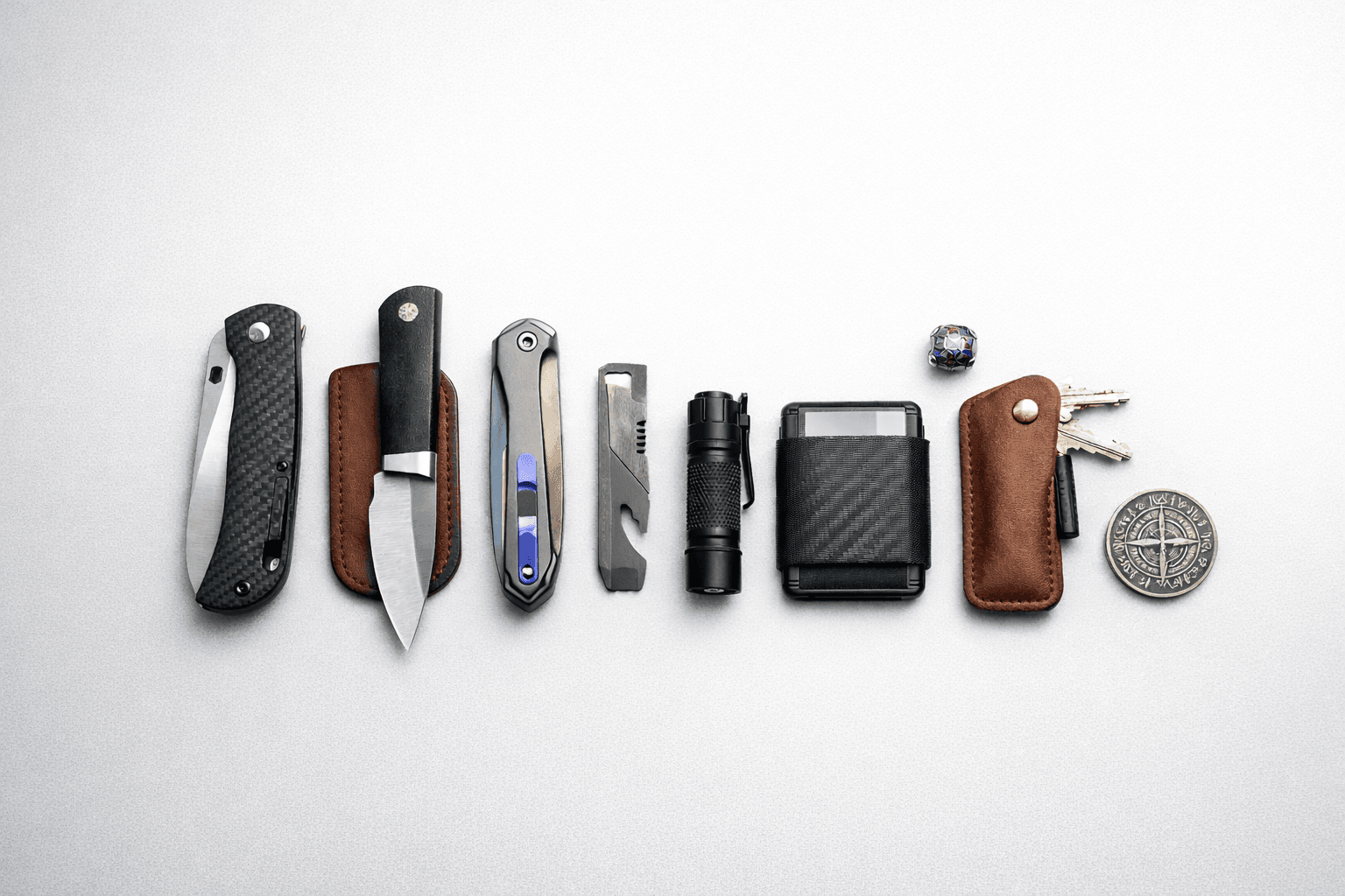 Curated carry assortment with knives, flashlight, wallet, tools, and slip